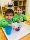 niños en aula infantil riendose y haciendo actividad sensorial con agua.